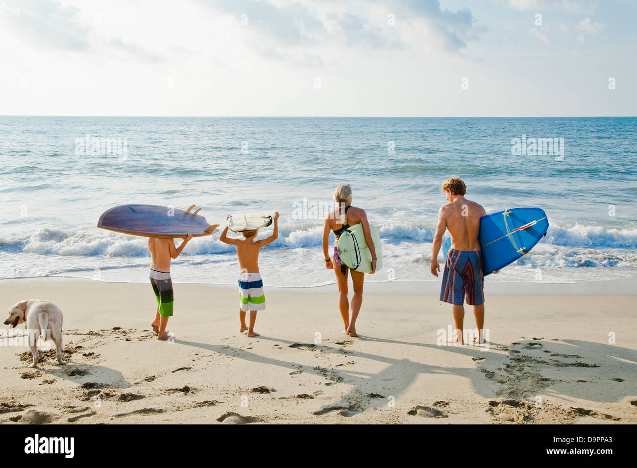 Family on beach holding surfboards Banque D'Images