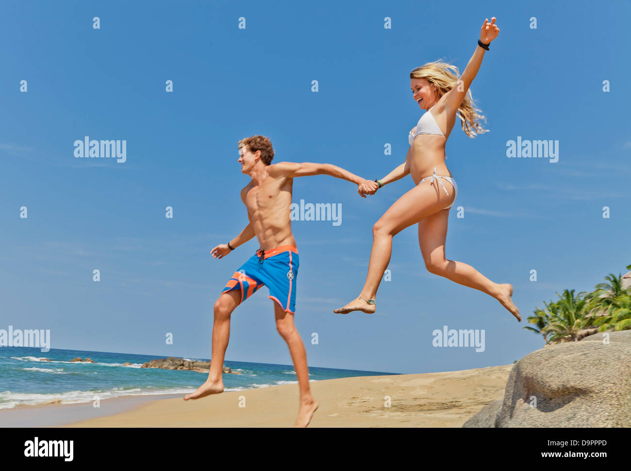 Young man and woman running on beach Banque D'Images