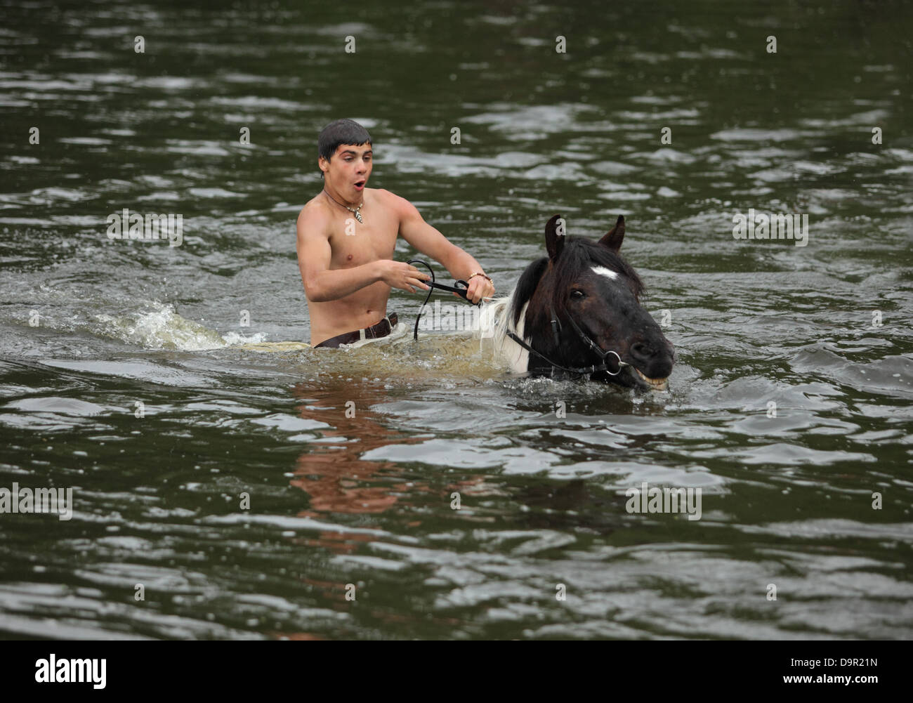 Garçon baigne son cheval dans la rivière Banque D'Images