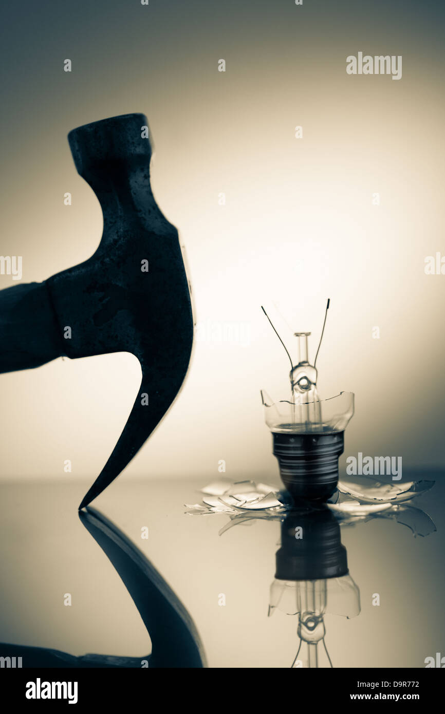 Silhouette marteau à côté de l'ampoule cassée Banque D'Images