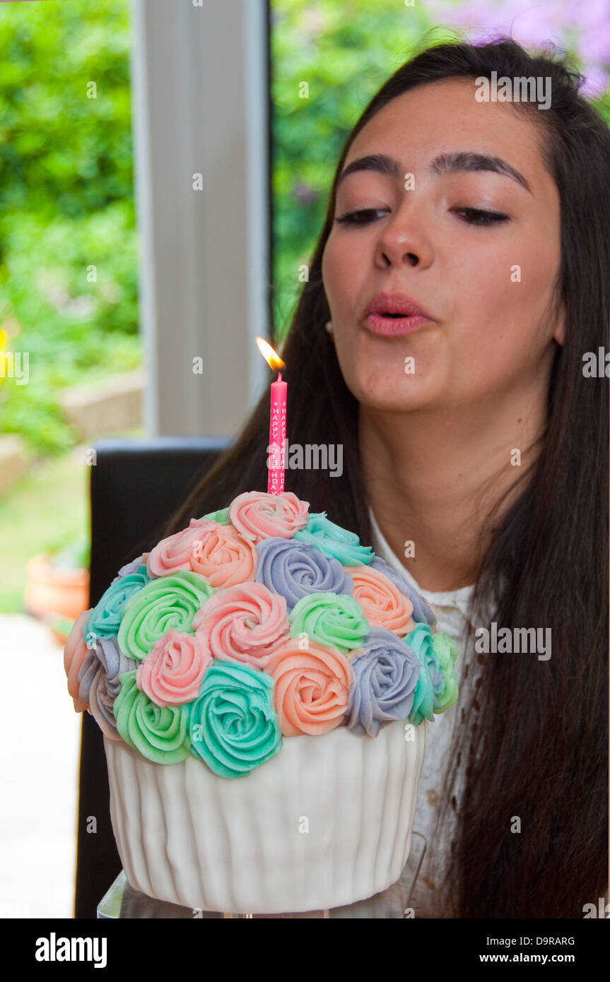 Close up portrait of Vertical un anniversaire girl blowing out la bougie sur son gâteau fait maison Banque D'Images