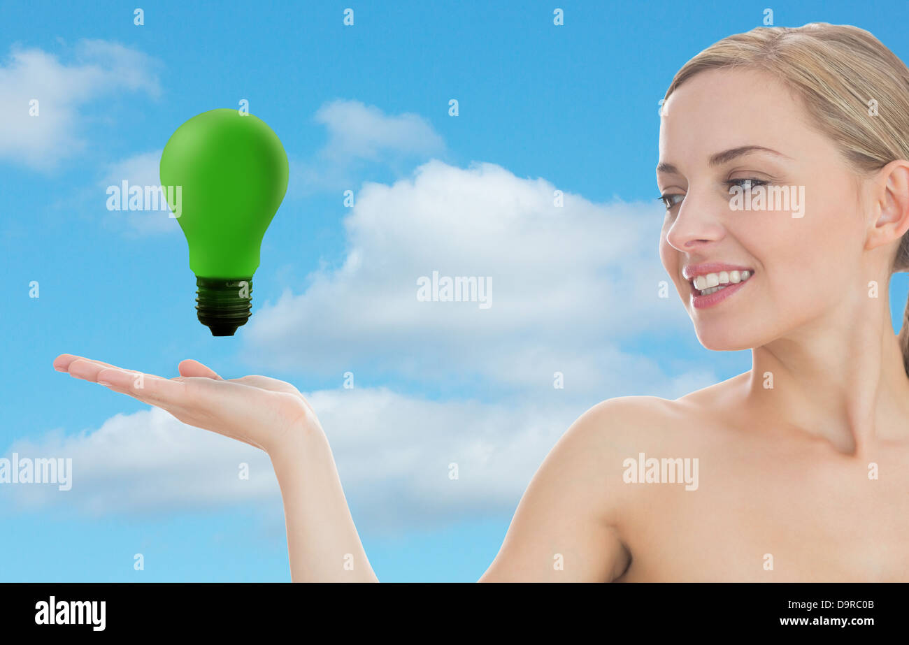 Smiling woman looking at green light bulb Banque D'Images Smiling woman looking at green light bulb Banque D'Images