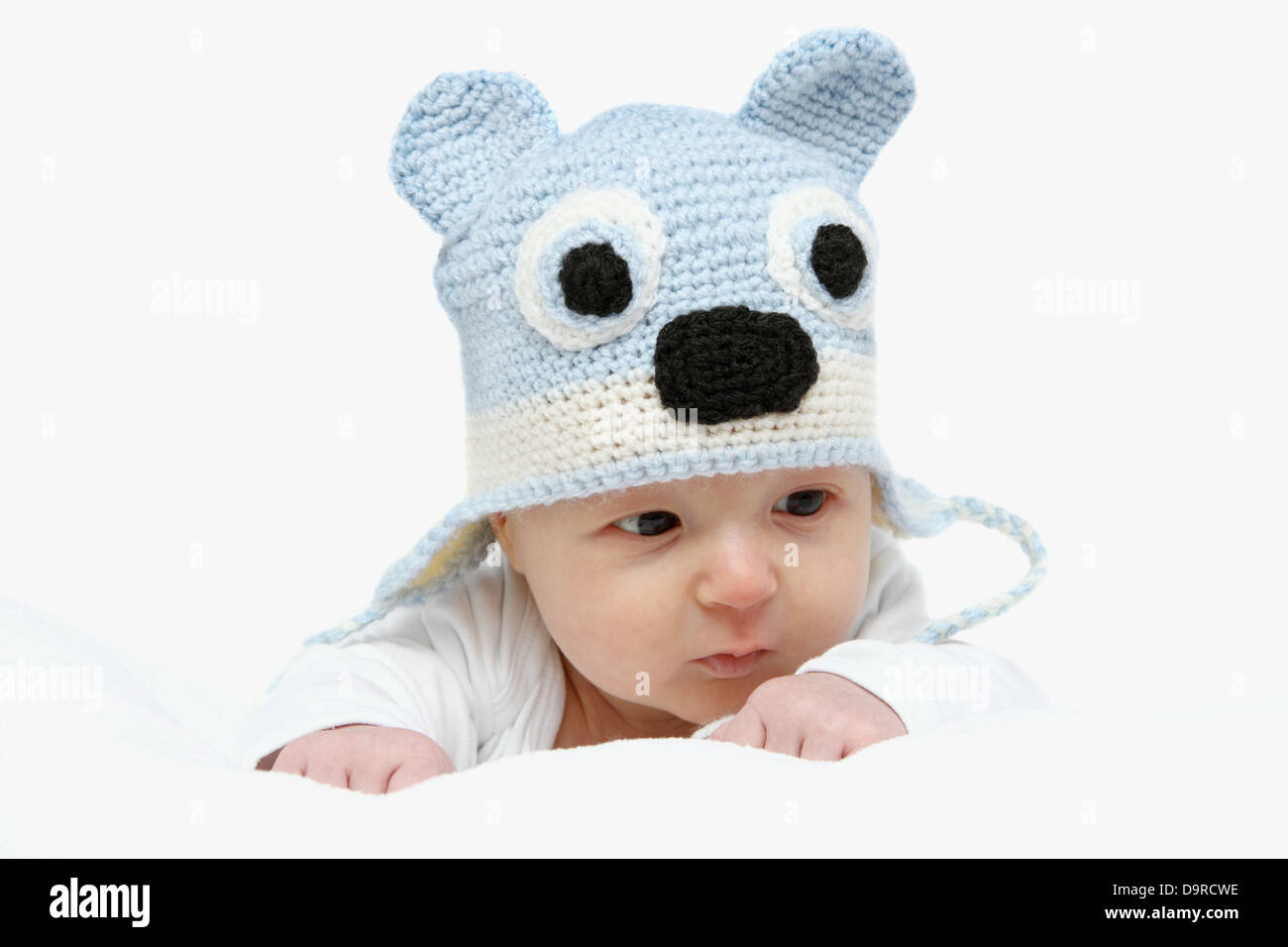 Bébé avec un chapeau bleu tricoté sur l'estomac Banque D'Images