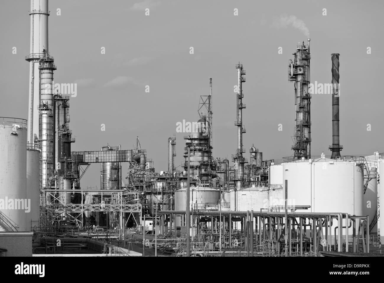 Les réservoirs de stockage de pétrole et de tours de distillation dans une raffinerie en journée. Image en noir et blanc. Banque D'Images