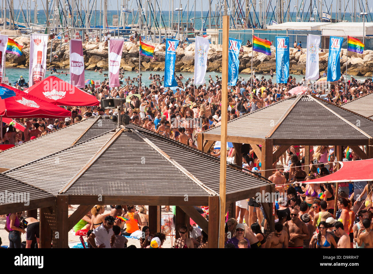 Israël Tel Aviv les célébrations de la Journée de la Fierté gaie foules se réunissent sur la plage mer Gordon par marina pour concert party parasols drapeaux LGBT Banque D'Images