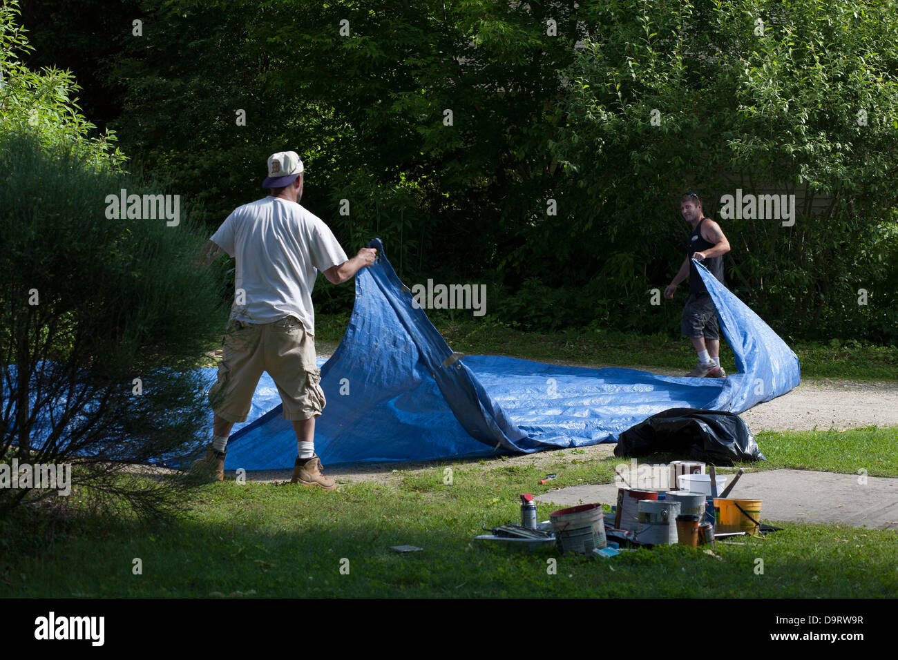 Par un après-midi d'été, deux hommes nettoyer après un travail de peinture. Ils sont leur pliage tissu avant qu'ils quittent le travail. Banque D'Images