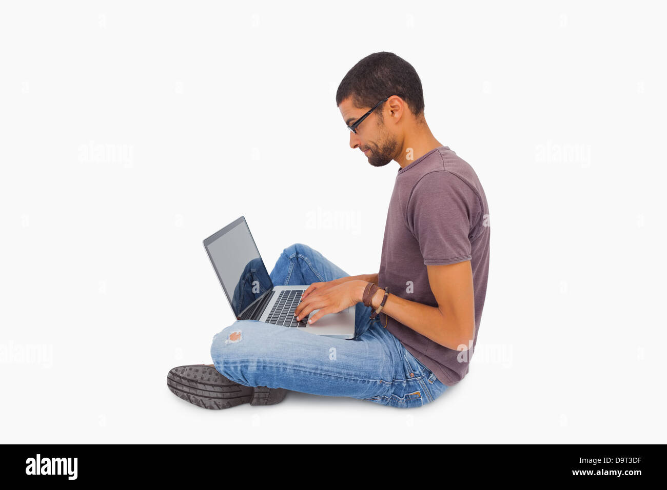 Man wearing glasses sitting on floor using laptop Banque D'Images