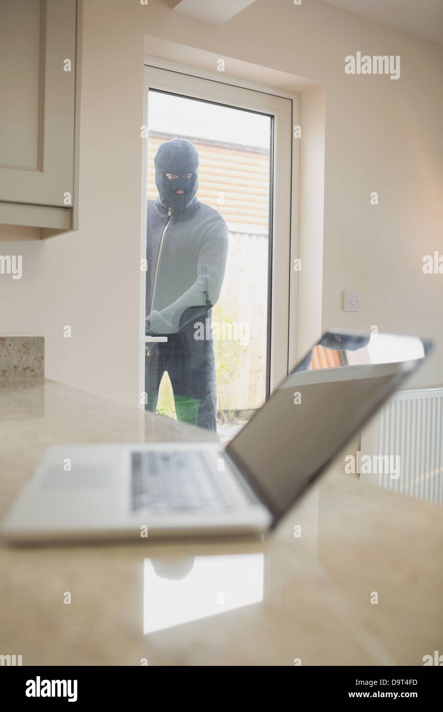 Burglar looking at laptop par la fenêtre Banque D'Images