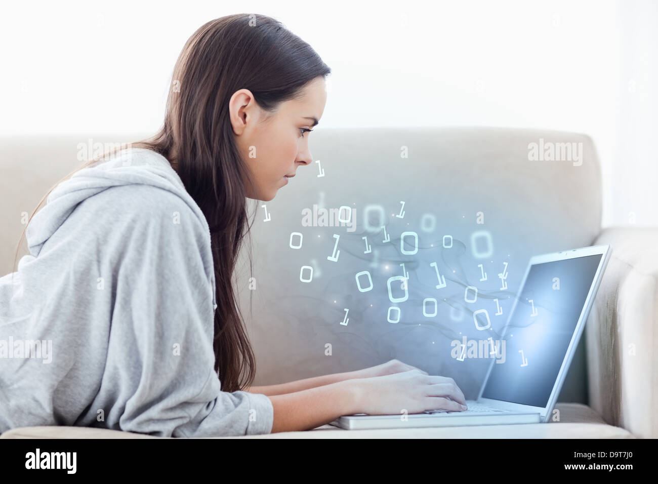 Woman using laptop with binary codes flottant au-dessus de Banque D'Images