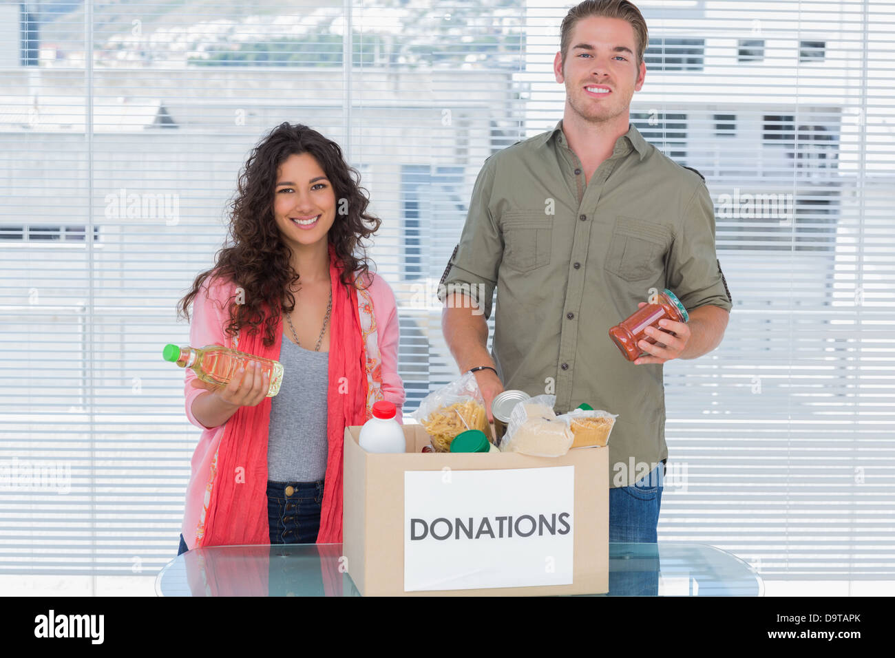 Des bénévoles souriant en tenant de la nourriture à partir de la boîte de dons Banque D'Images