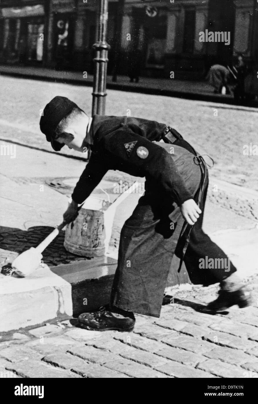 Un garçon, portant l'uniforme de la Jeunesse allemande, peint des bordures de trottoir pour la protection contre les attaques aériennes ennemies, en août 1940, à Berlin. Fotoarchiv für Zeitgeschichte Banque D'Images