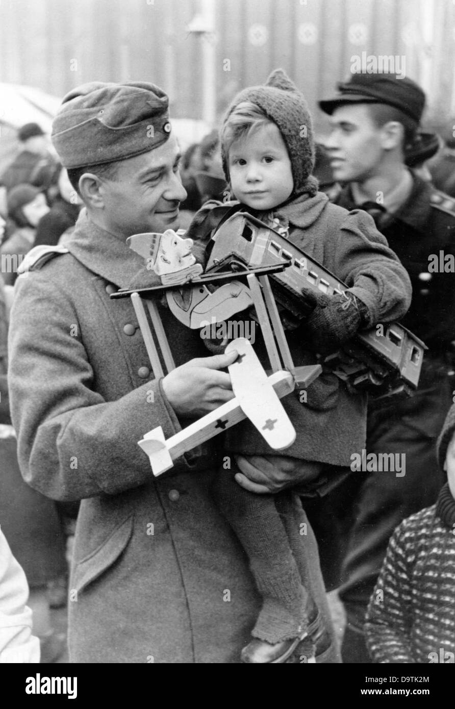 Un soldat allemand de Wehrmacht à bord de la fourrure transporte son enfant autour du marché de Noël dans le Berlin Lustgarten en hiver 1942. Fotoarchiv für Zeitgeschichte Banque D'Images