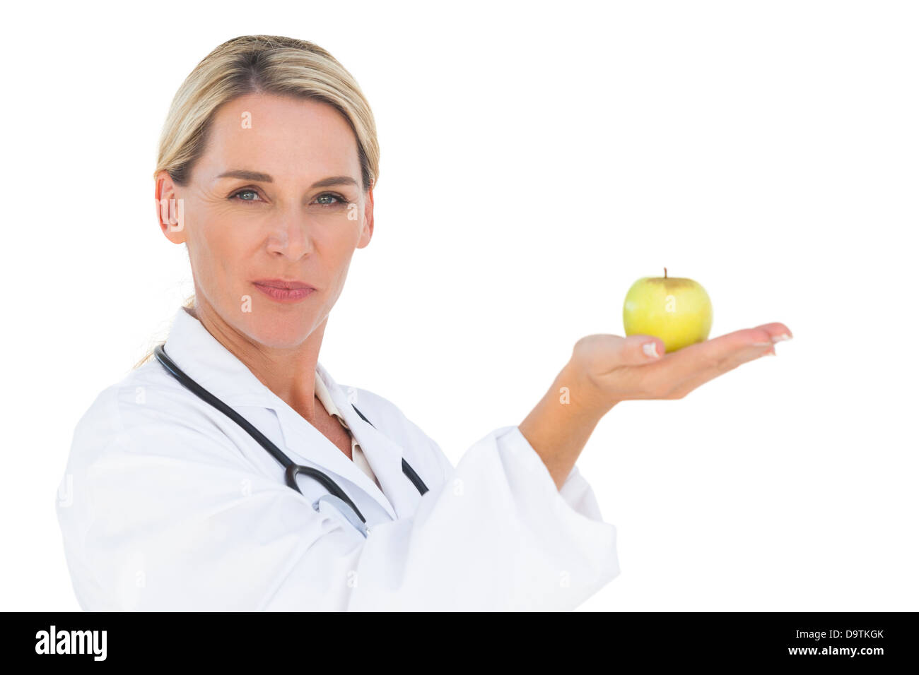 Happy doctor holding out green apple and looking at camera Banque D'Images
