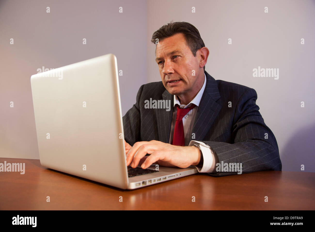 L'homme d'affaires à maturité à un bureau à l'aide d'un ordinateur portable. Banque D'Images