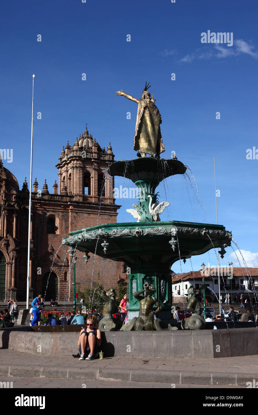 Assis à côté de tourisme fontaine avec statue de Pachacuti Yupanqui Inca Pachacutec, ou cathédrale en arrière-plan , Cusco, Pérou Banque D'Images