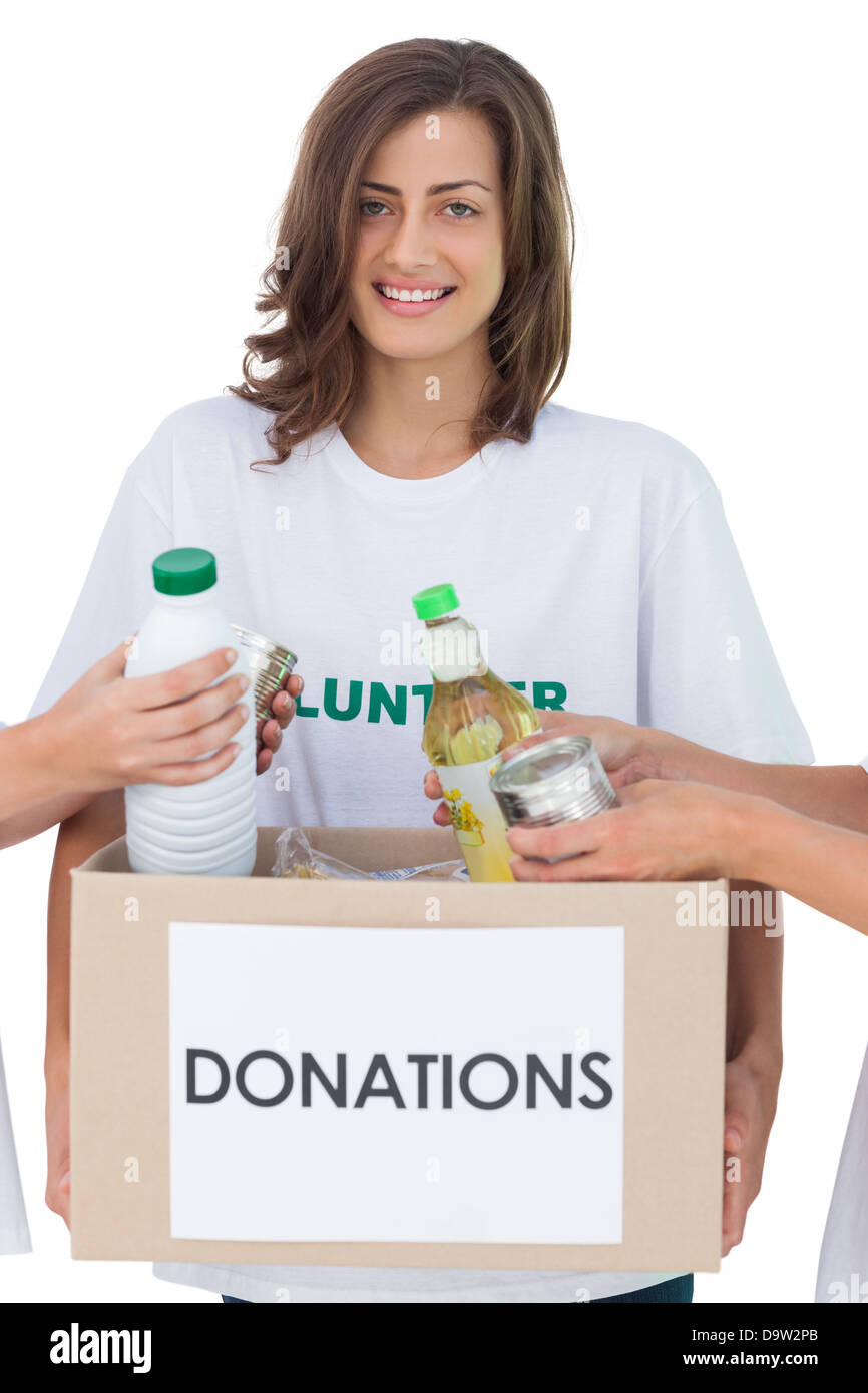 Des bénévoles souriant tenant une boîte de dons alimentaires Banque D'Images