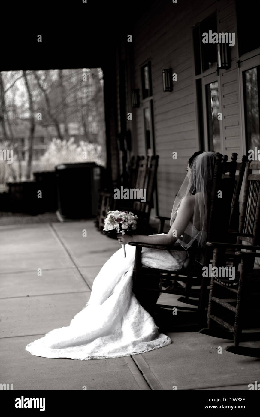 Une épouse qui attend dans le fauteuil à bascule sur le porche de la cérémonie organisée pour commencer. Banque D'Images