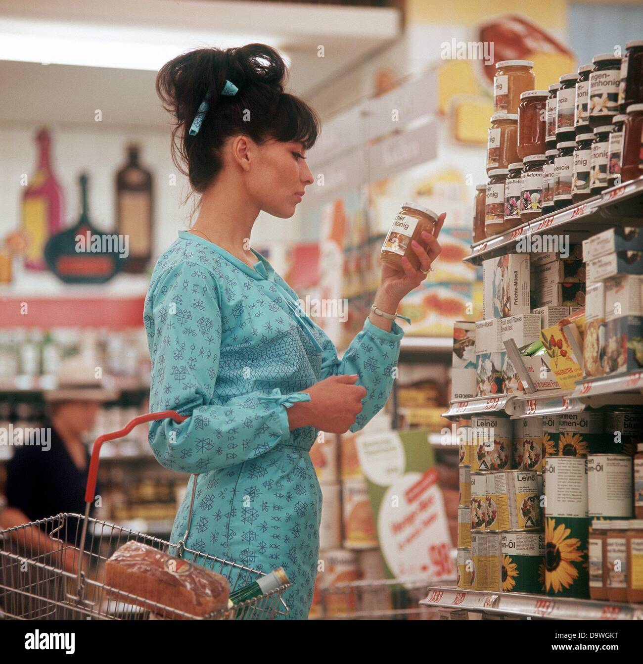 Une jeune femme a un verre de miel dans sa main dans un magasin libre-service (sans date photo à partir des années 1970). Banque D'Images