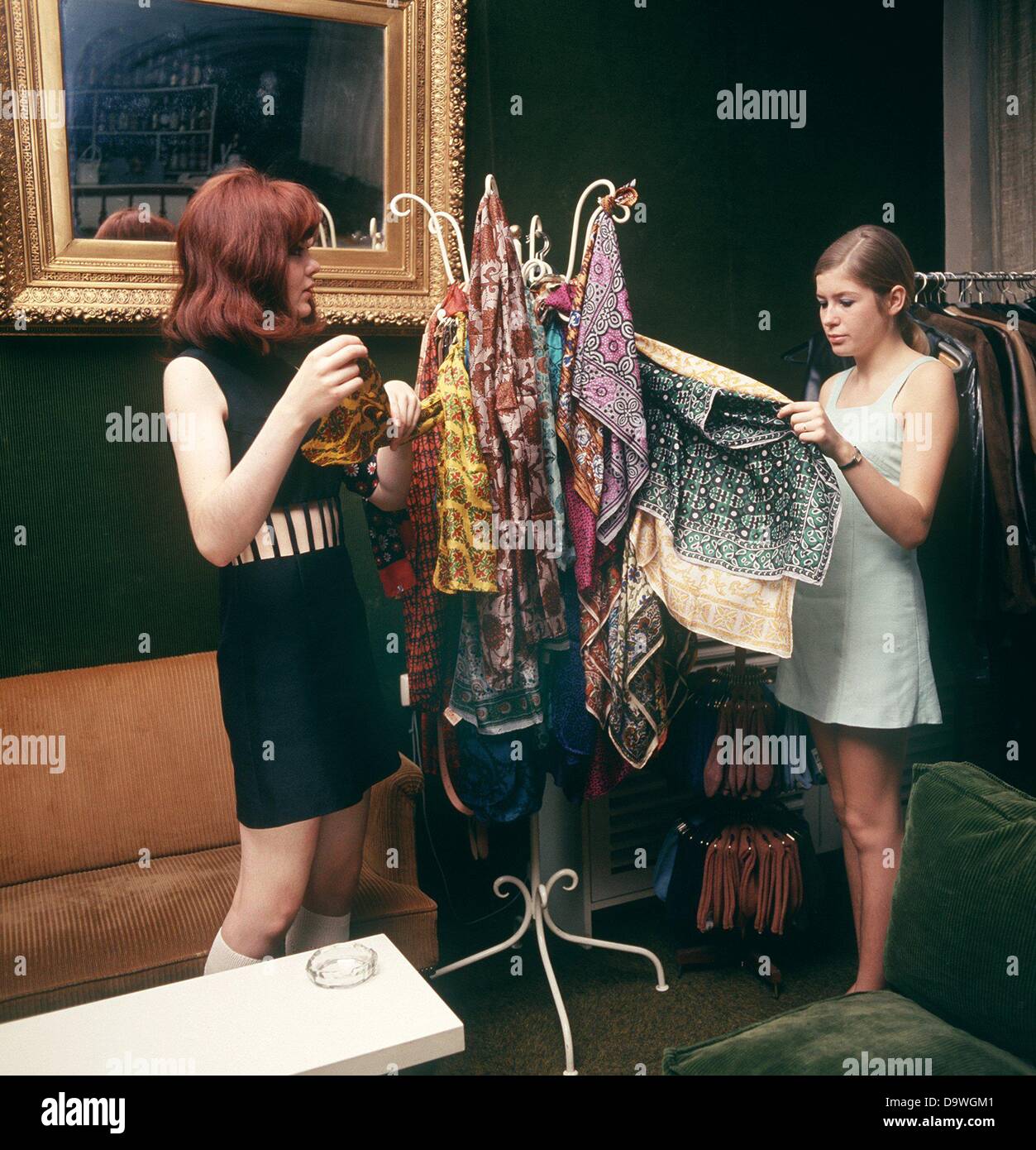 Deux jeunes femmes ont un regard sur l'offre de tissus colorés dans le Fashion Boutique Napoléon, photographiés dans le début des années 70. Banque D'Images
