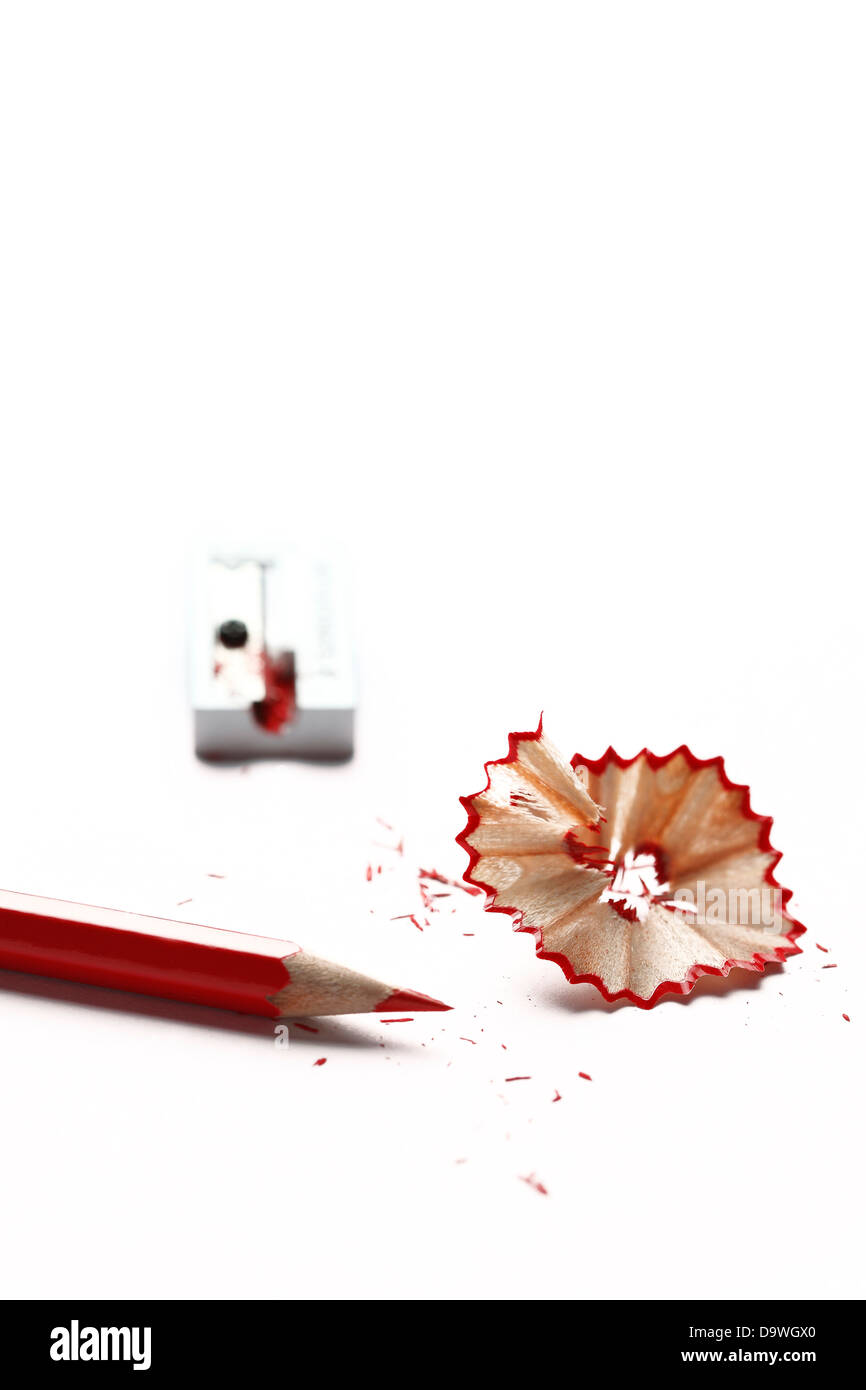 Aiguisé crayon rouge et copeaux avec aiguiseur hors focus Banque D'Images