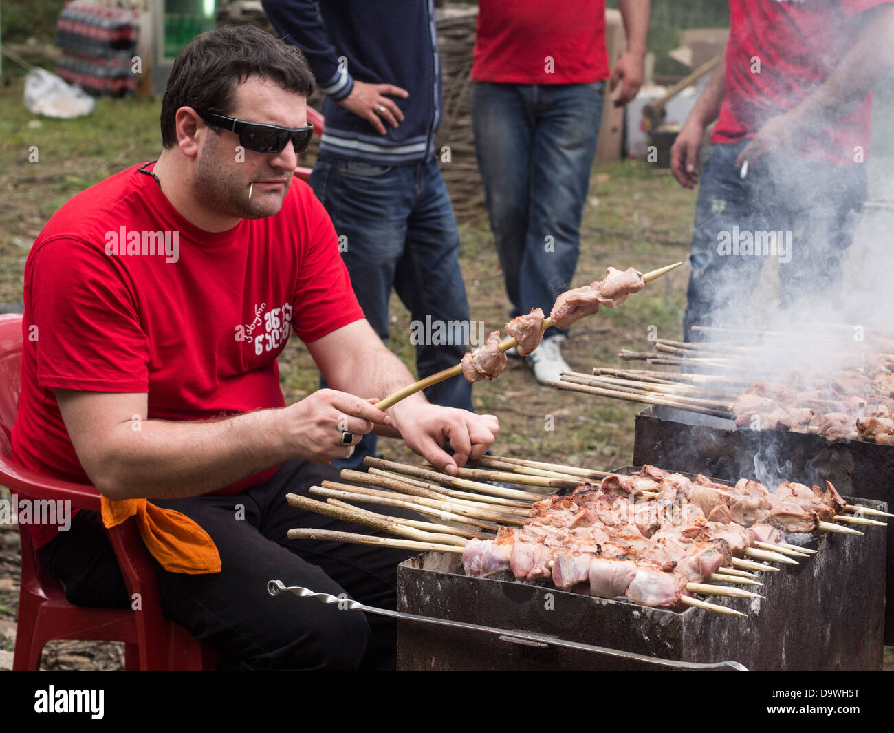 Géorgiens préparer un de leurs plats nationaux, l'mtsvadi (grillades brochette de viande), sur les jeunes Festival du vin à Tbilissi. Banque D'Images