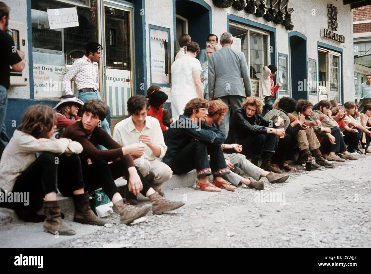 Les mocassins assis sur le trottoir en face de l'aire de pique-nique '', un lieu de rencontre populaire pour les mocassins et scène hippie dans la rue Léopold à Munich (photo de 1970). Banque D'Images