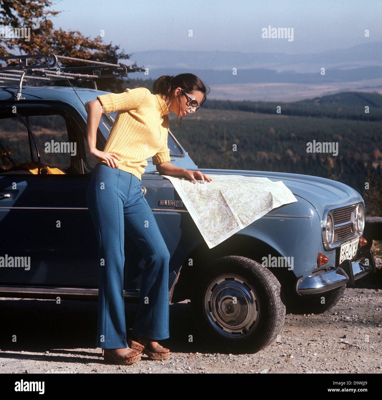 Une jeune femme se tient debout devant sa voiture à Brigge Olsberg et informe elle-même en regardant une carte (photo de 1970). Banque D'Images