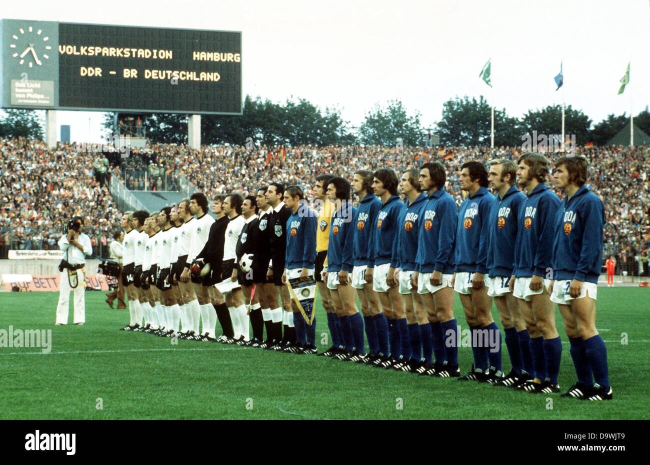 Les équipes de soccer de l'Allemagne de l'Ouest et se tenir dans des fichiers pour les hymnes nationaux avant le début de la Coupe du Monde 1974 jeu de football contre l'Allemagne de l'ouest de l'Allemagne à Hambourg, Allemagne, 22 juin 1974. L'Allemagne de l'Ouest, à partir de L : milieu de terrain Uli Hoeness, défenseur Paul Breitner, défenseur Berti Vogts, Juergen avant le milieu de Grabowski, Wolfgang Overath, Gerd Mueller, Heinz Flohe avant, défenseur Georg Schwarzenbeck, défenseur Bernd Cullmann, gardien Sepp Maier, défenseur Franz Beckenbauer, arbitre uruguayen Ramon Barretto Ruiz (avec ballon dans ses mains). L'Allemagne de l'Est, à partir de L : defe Banque D'Images