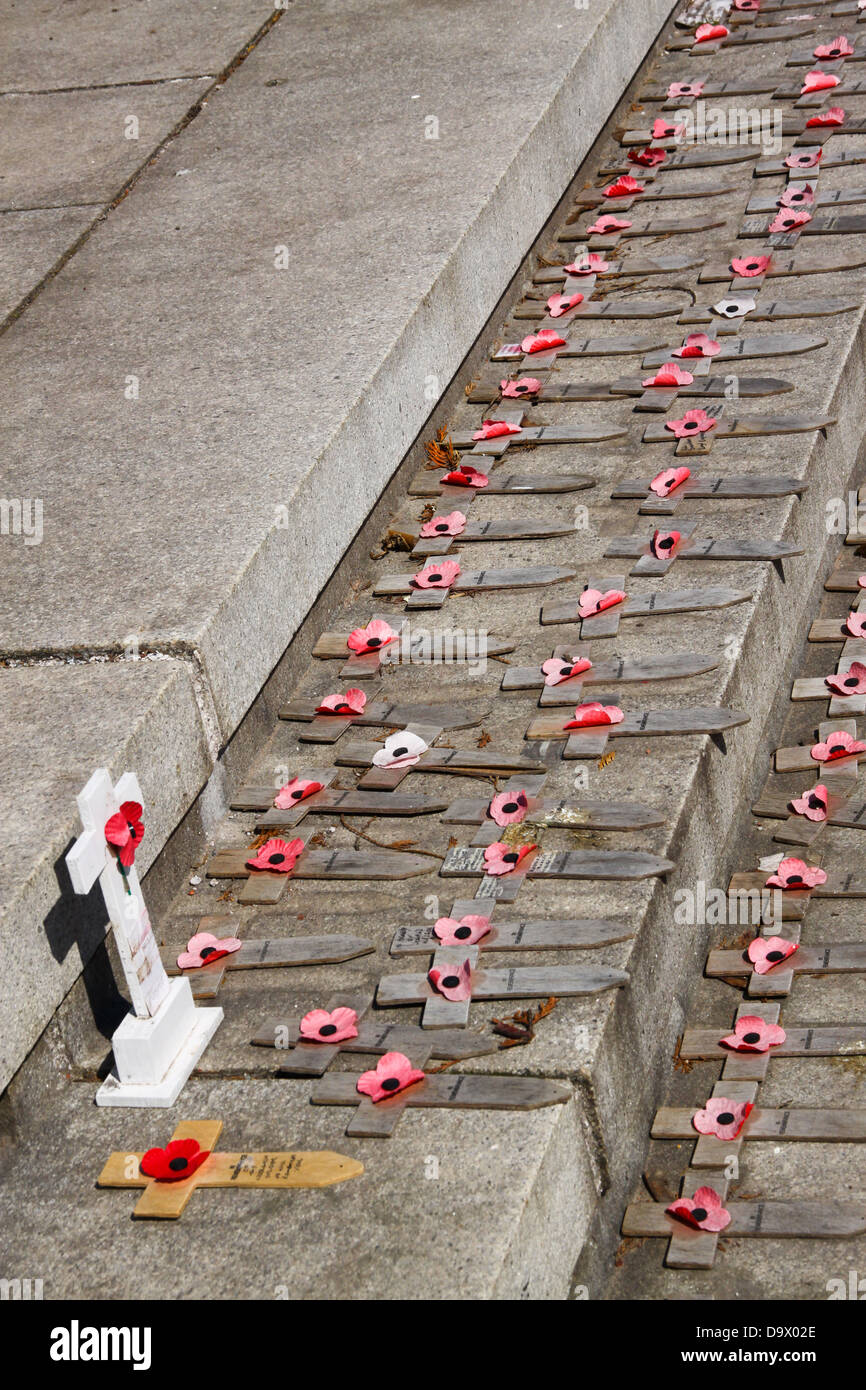 Petite croix de bois décoloré et coquelicots sur war memorial Banque D'Images