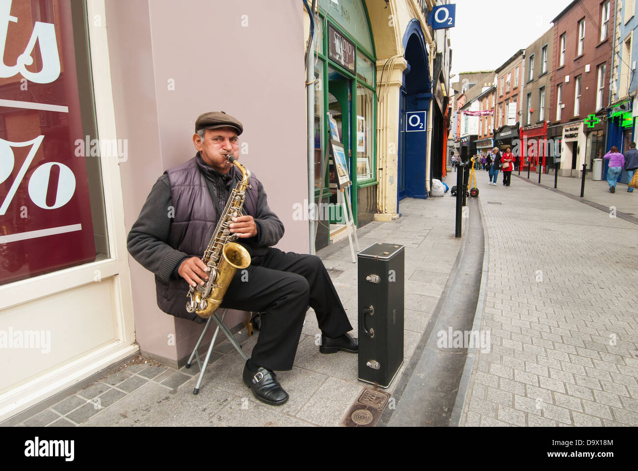 Un homme fait un saxophone le long d'une rue ; Ireland Banque D'Images