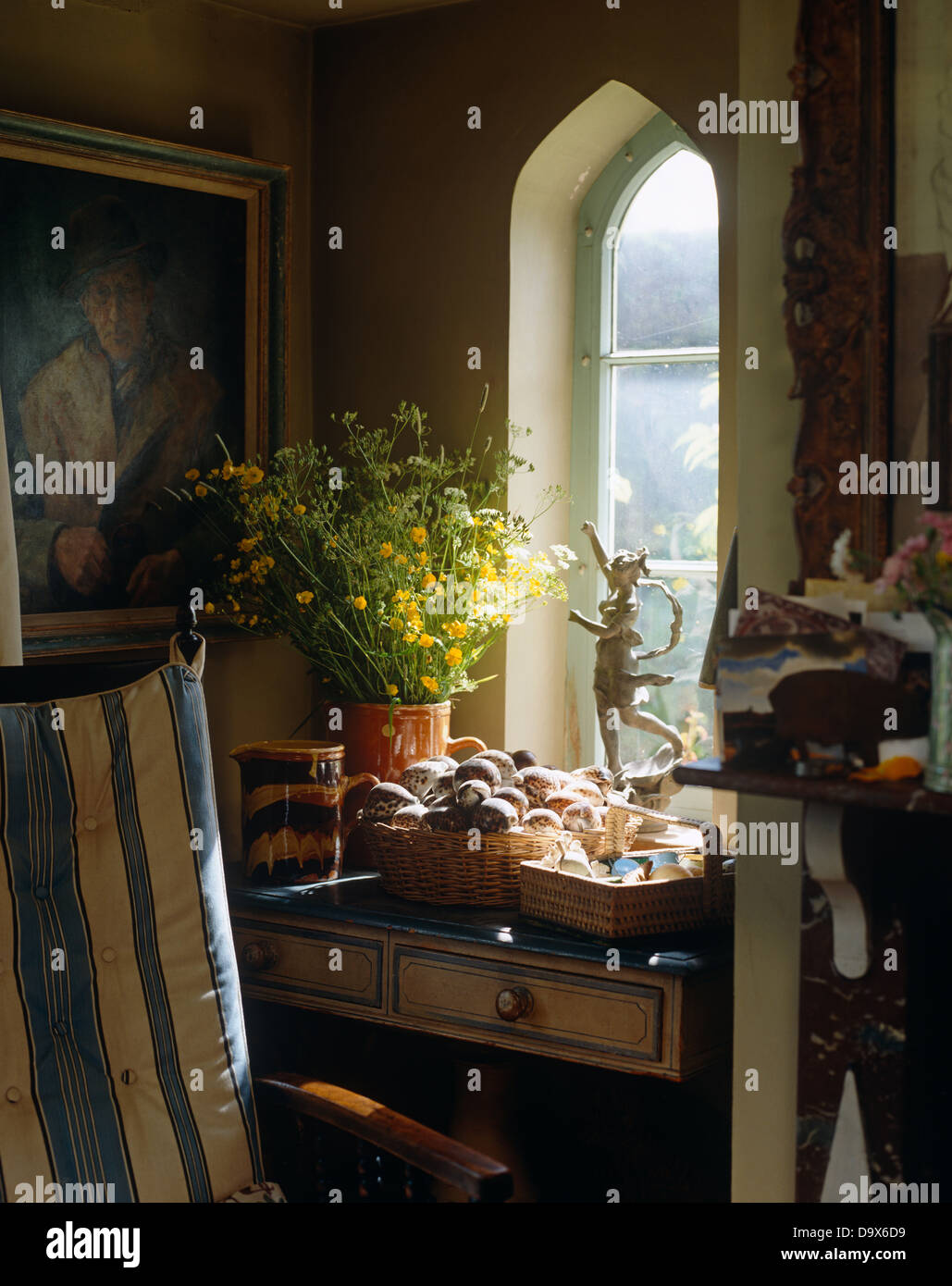 Vase de renoncules et corbeille de fruits à l'ancienne table en bois en dessous de la peinture à l'huile et fenêtre cintrée en cuisine cottage Banque D'Images