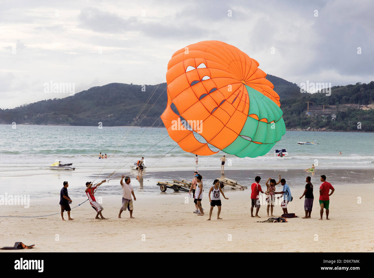 PATONG Beach, Phuket, Thaïlande 14 AOÛT 2011 : un groupe d'opérateurs du parachute ascensionnel préparer un client pour un tour. Banque D'Images