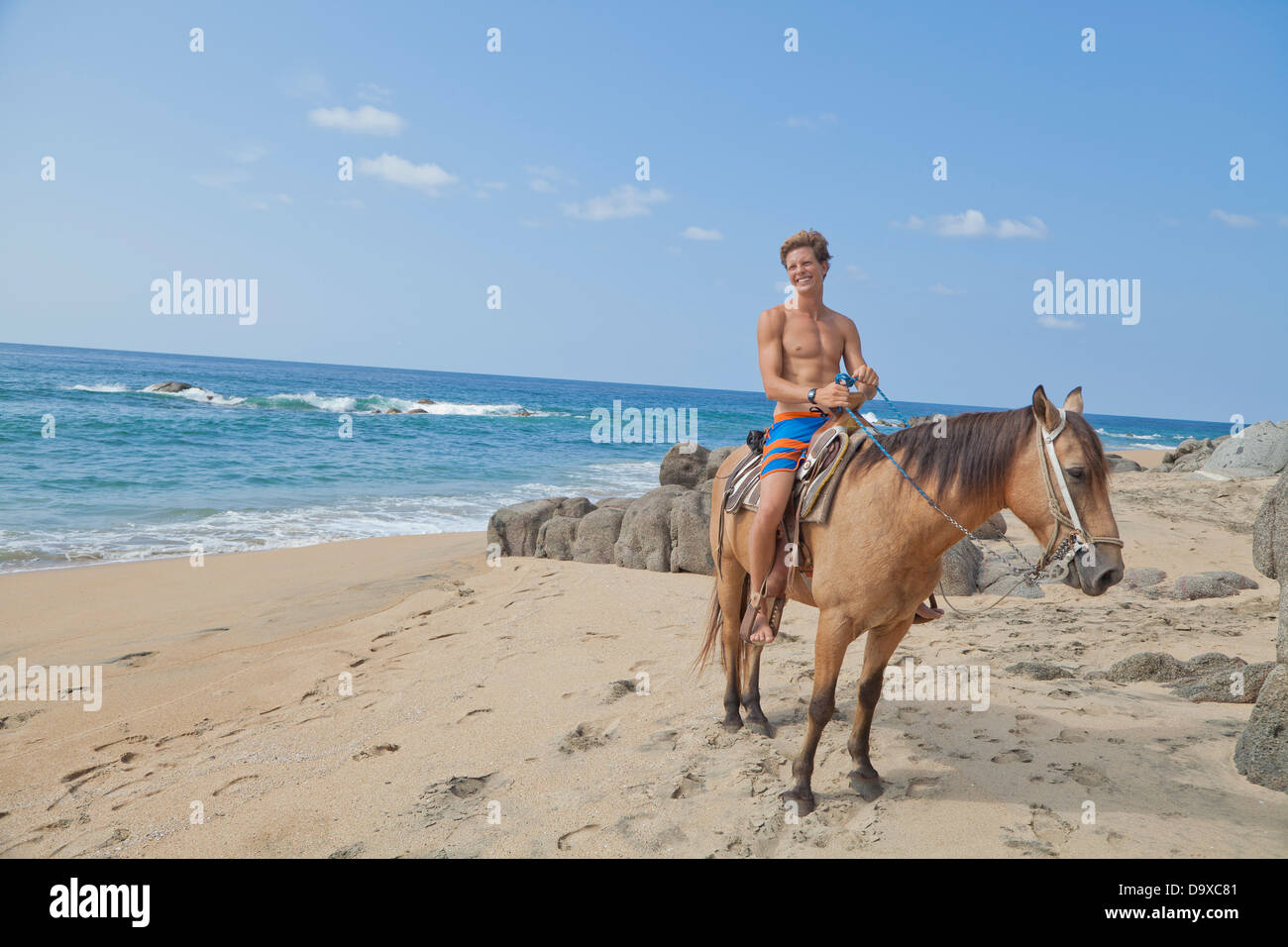 Jeune homme riding horse on beach Banque D'Images