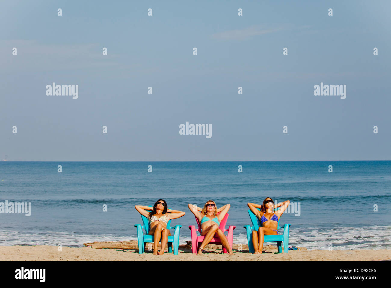 Trois femmes se prélasser sur les chaises de plage Banque D'Images