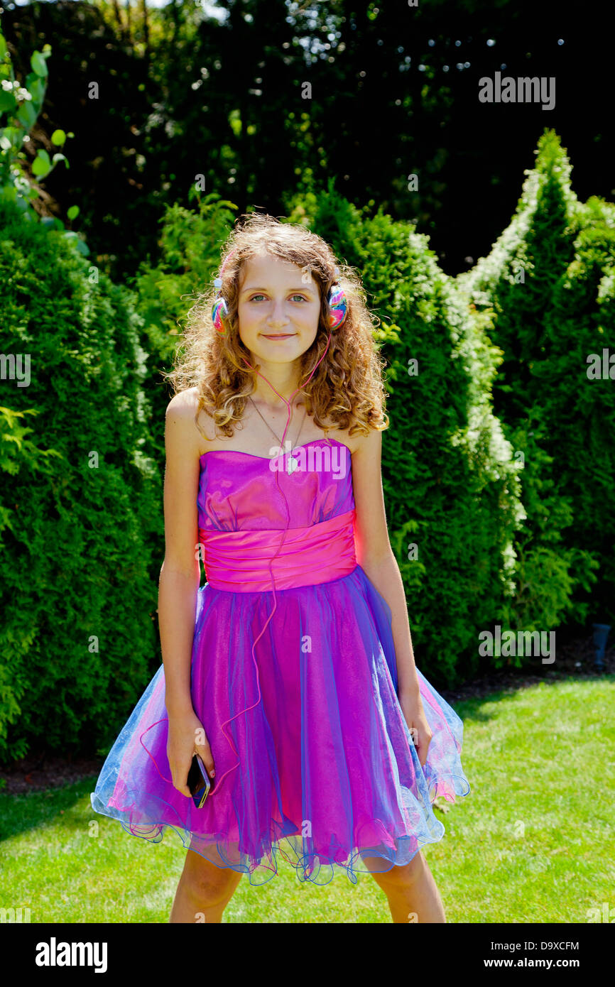Teen girl in party dress écouter de la musique en plein air Banque D'Images