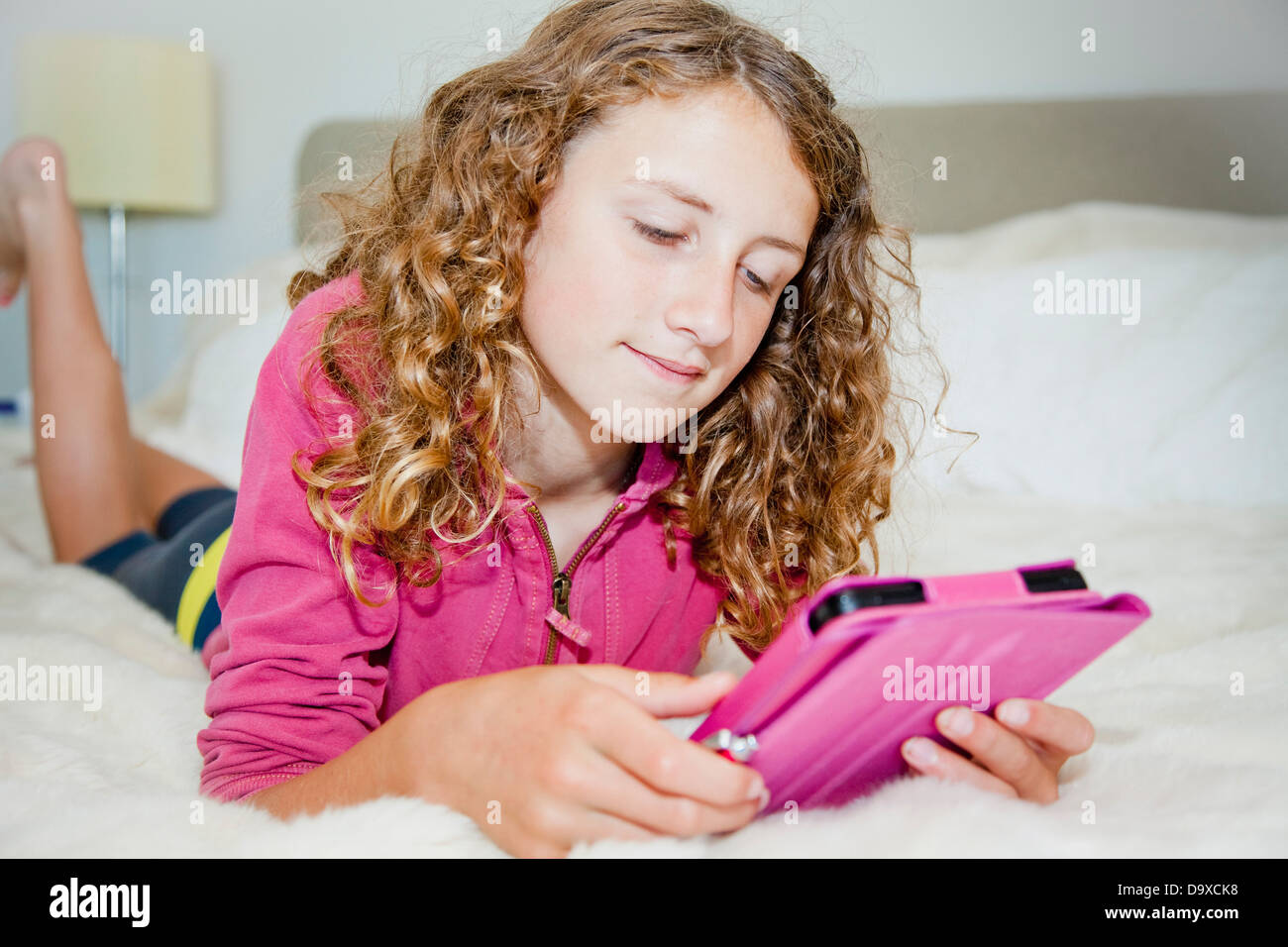 Teen girl on bed with tablet Banque D'Images