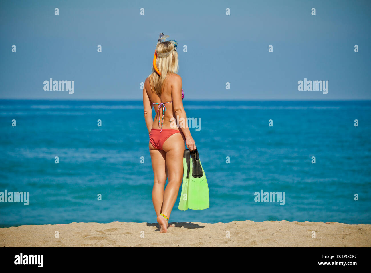 Woman walking on beach transportant des nageoires nage Banque D'Images