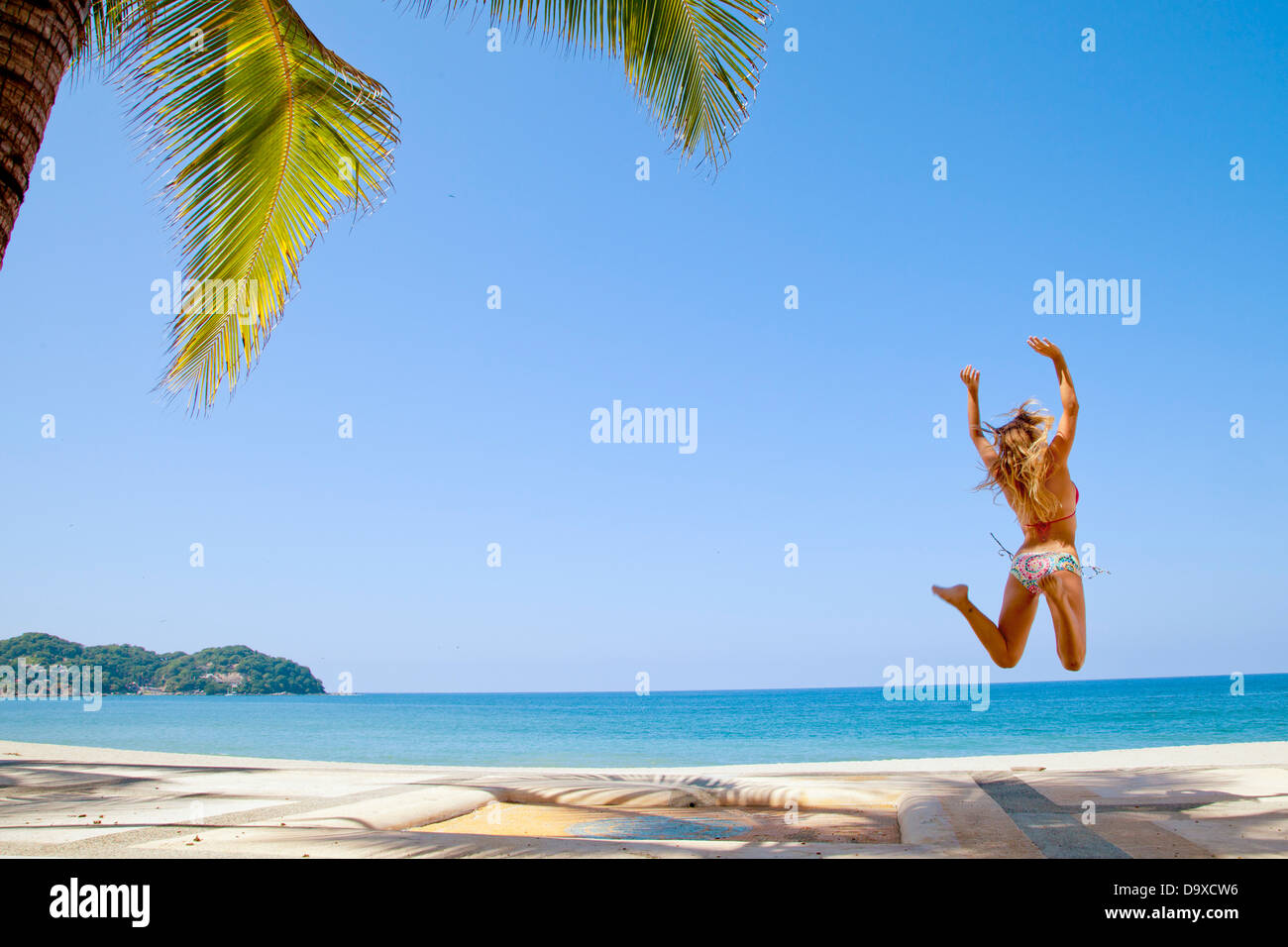 Woman in bikini jumping on beach Banque D'Images