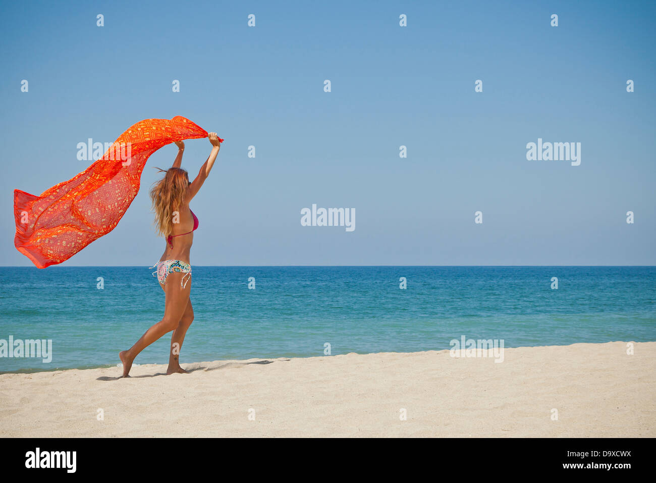 Woman running on beach holding sarong Banque D'Images Woman running on beach holding sarong Banque D'Images