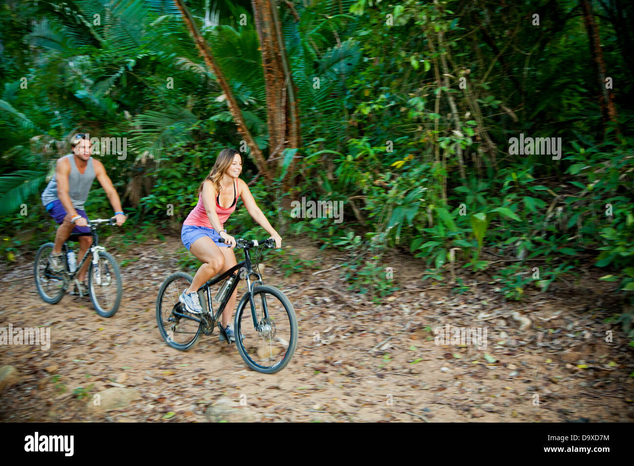 Couple riding bicycles sur chemin de la jungle Banque D'Images