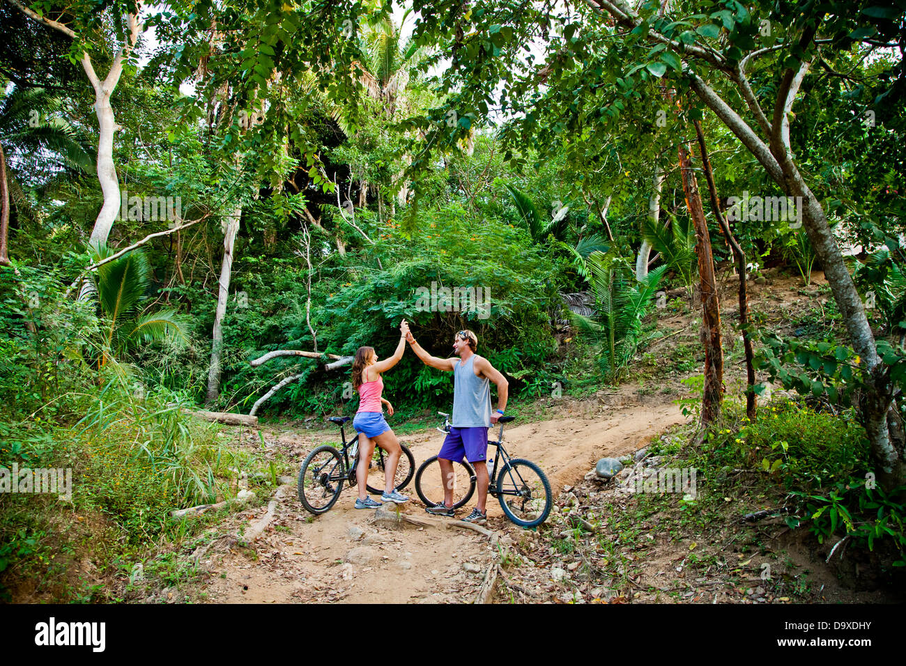 Couple riding bicycles sur chemin de la jungle Banque D'Images