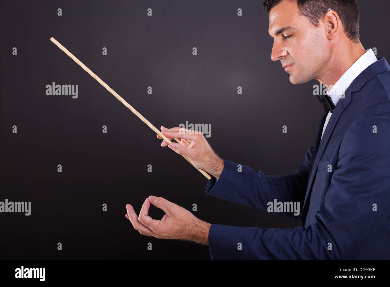 Homme orchestre avec les yeux fermés sur fond noir Banque D'Images