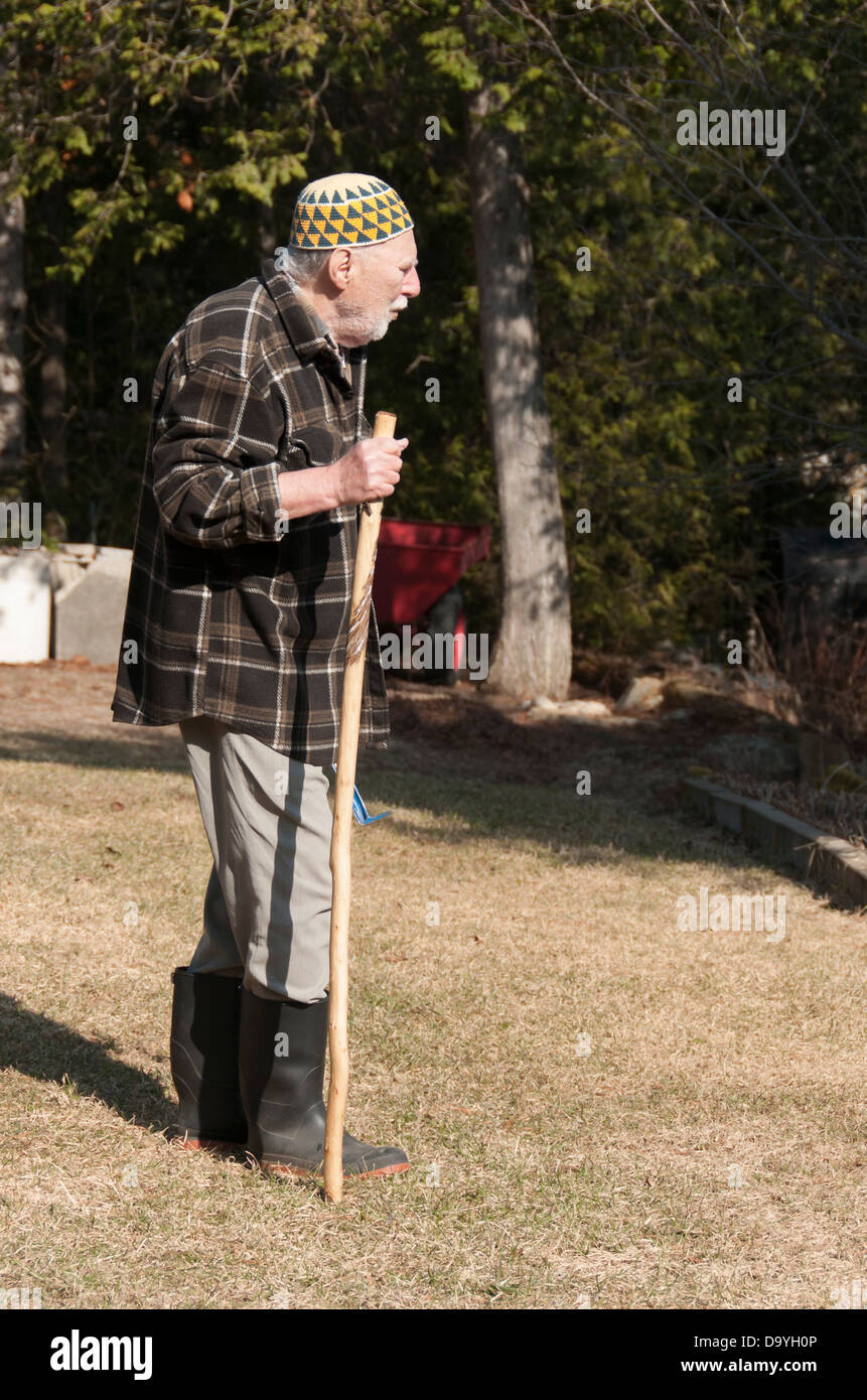 Vieil homme avec chapeau et kufi stick marche sur son jardin Banque D'Images