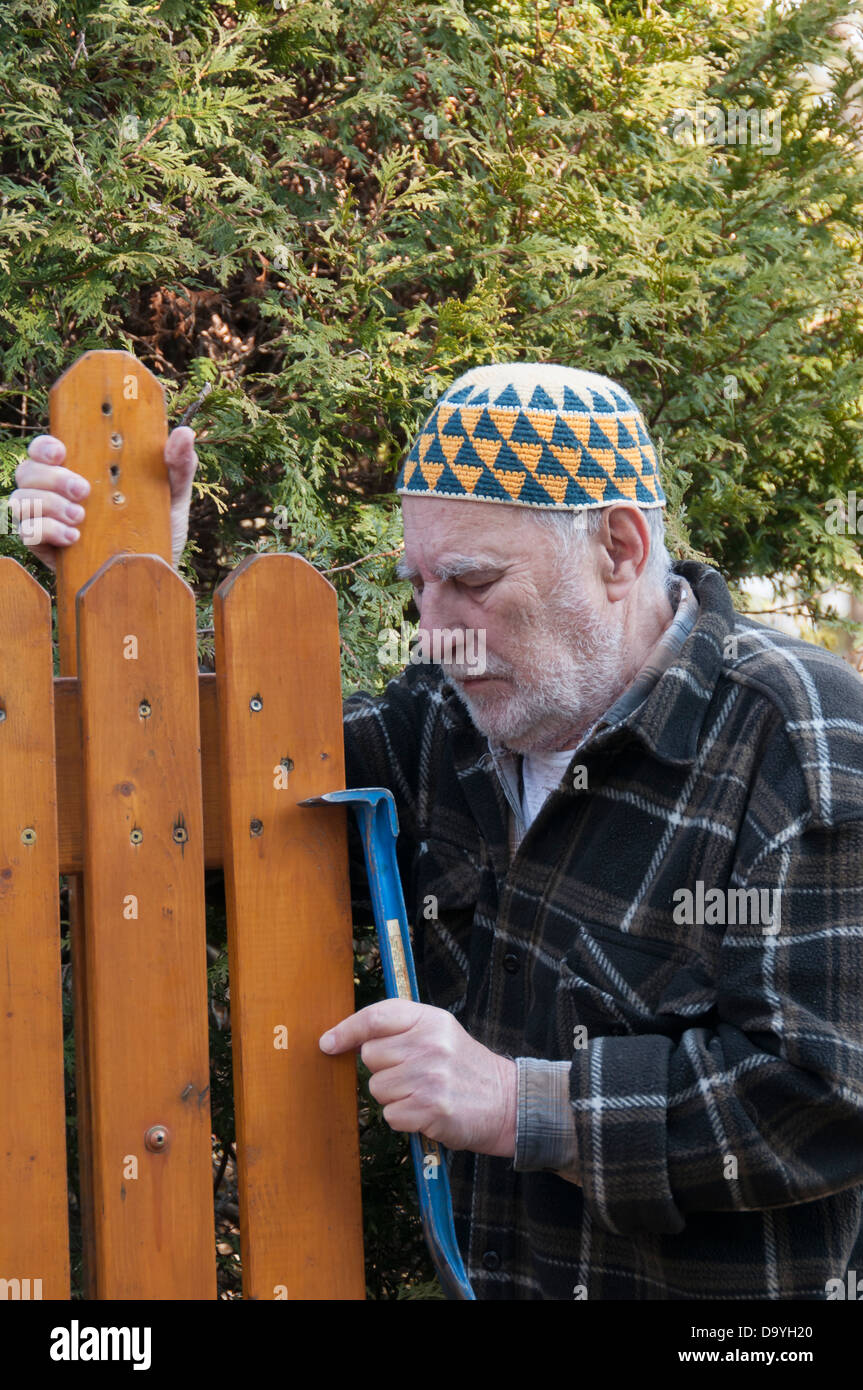 Vieil homme avec un chapeau et de l'outil réparation kufi la porte de sa  maison Photo Stock - Alamy