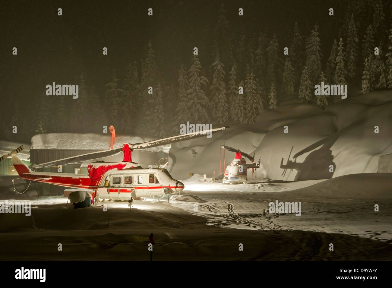 Les hélicoptères utilisés pour l'héliski parqué dans de fortes chutes de neige dans la nuit. Banque D'Images