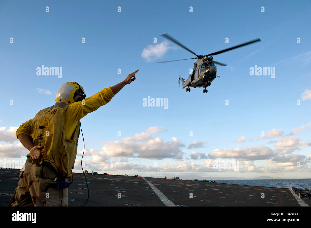 Marin de la marine des États-Unis des signaux à une armee de terre SA 380 Puma hélicoptère comme il décolle de l'amphibious landing ship dock USS Pearl Harbor le 28 juin 2013 à Nouméa, Nouvelle-Calédonie. Banque D'Images