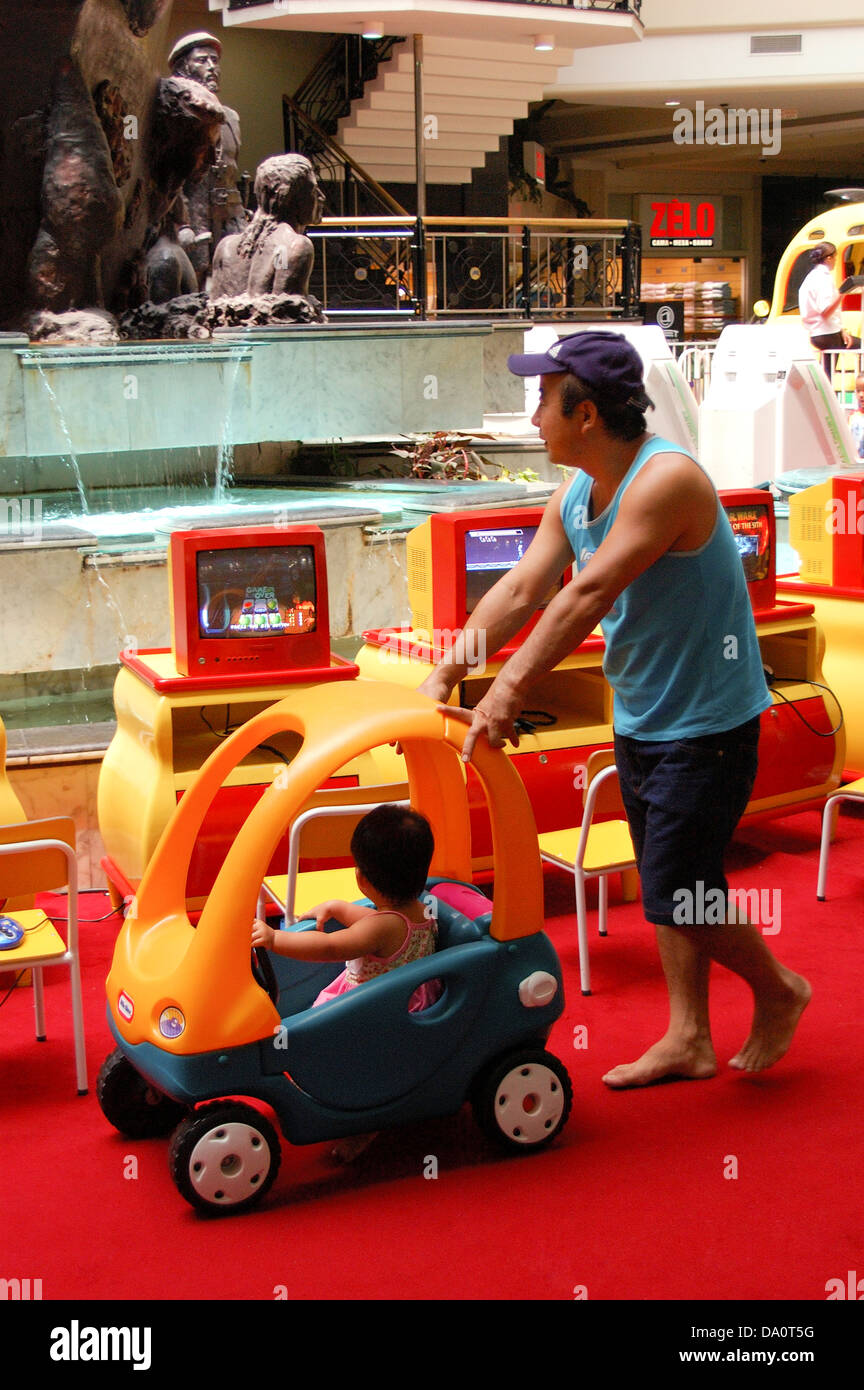 Père aidant tout-petit à monter une petite voiture à l'intérieur d'une maison un shopping mall Banque D'Images