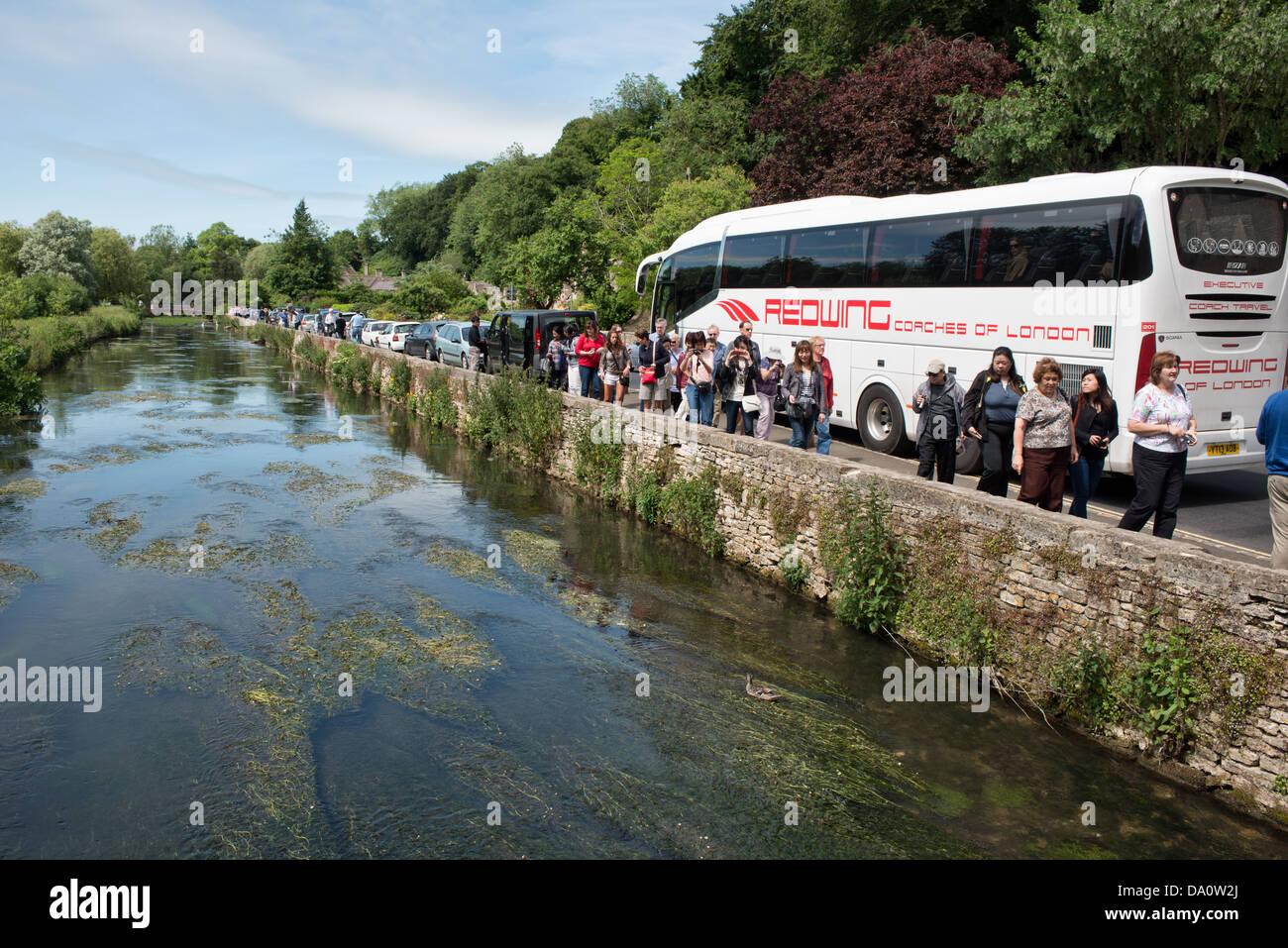 Une partie de l'entraîneur les touristes asiatiques arrivant par la rivière Colne dans le joli village de Cotswold Bibury, Gloucestershire, Royaume-Uni Banque D'Images