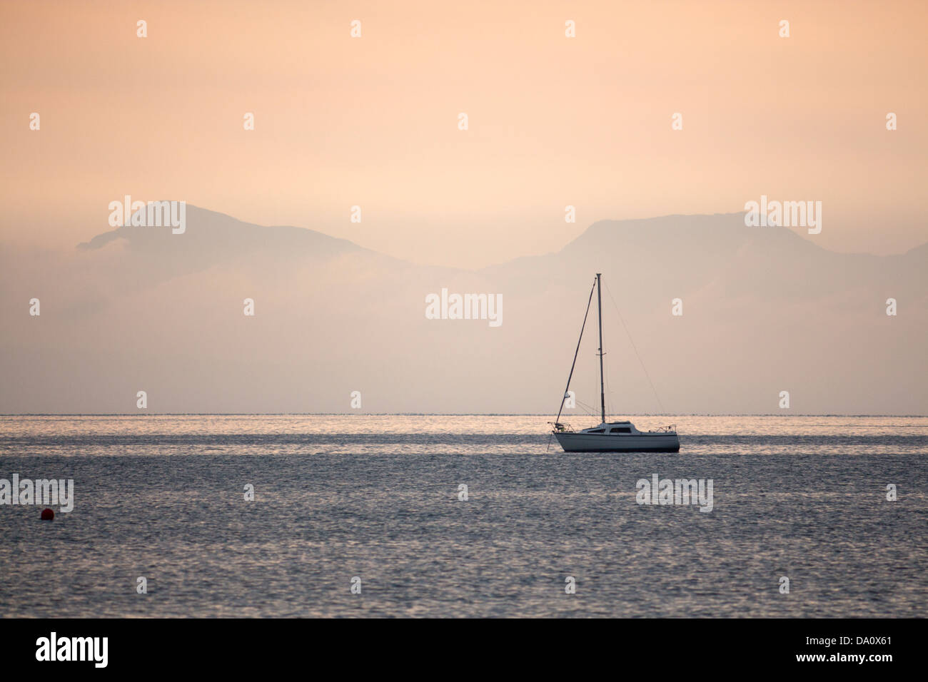 Bateau solitaire dans la baie de Tremadog avec Rhinog au lever du soleil derrière les montagnes brumeuses Snowdonia Gwynedd au nord du Pays de Galles UK Banque D'Images