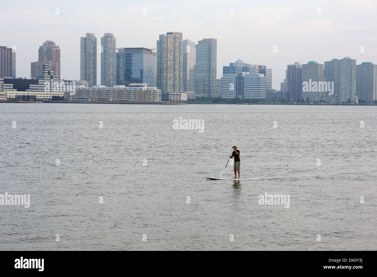 Un homme pagayer sur la rivière Hudson à New York Harbor. Jersey City est à l'arrière-plan. Banque D'Images